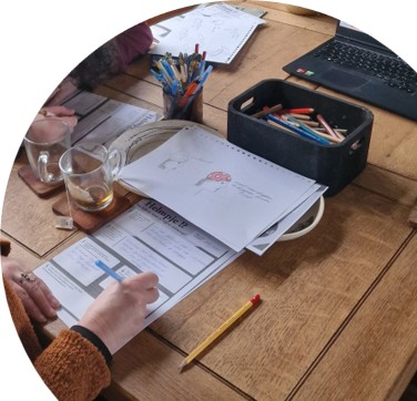 Participants filling in workshop worksheets with colored pencils on a wooden table