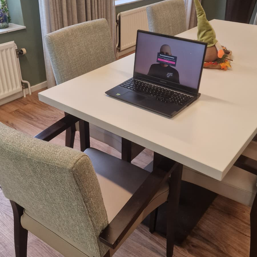 A laptop running the avatar prototype on a dining table in a living room